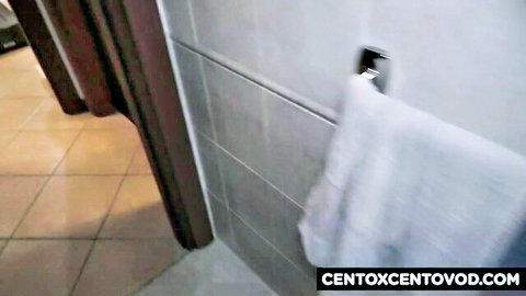 Empty tiled bathroom stall with white towel hanging on hook in amateur Italian porn video