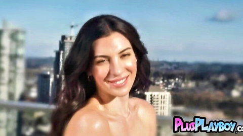 Topless curvy Latina babe with big tits smiling seductively on outdoor balcony city skyline
