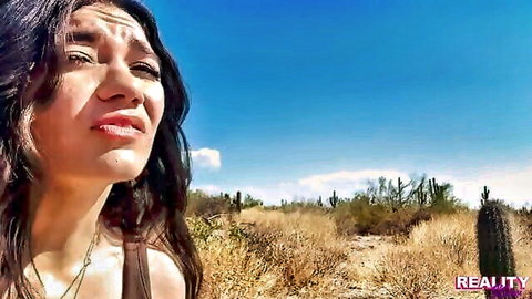 Emotional Latina woman in tank top, crying in sunny desert landscape