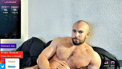 Bald muscular bearded hunk with hairy chest lounging shirtless on live webcam show
