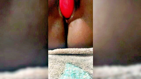 Close-up of black woman's creamy pussy with red toy insertion