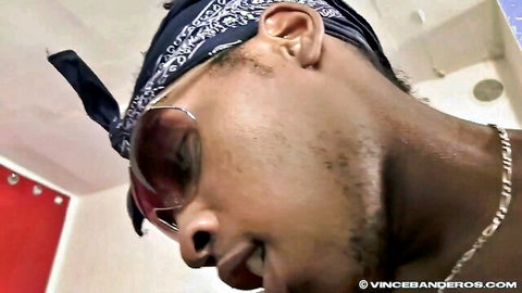 Close-up of Black man in blue bandana and sunglasses smirking in steamy bathroom