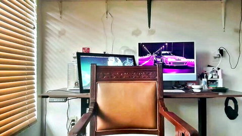 Empty webcam studio desk setup with leather chair and glowing monitors in cozy room