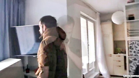 Bearded man in brown hooded jacket stands in modern apartment kitchen from Czech Hunter.