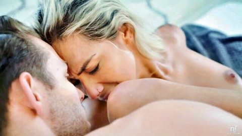 Blonde babe with perky tits passionately kissing nude muscular man in bed
