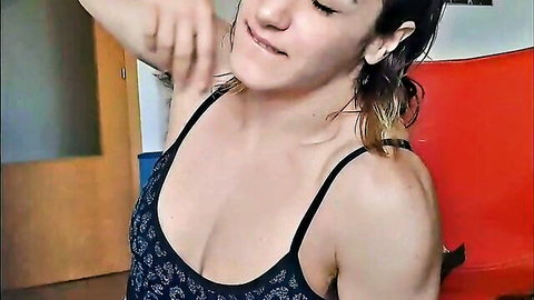 Amateur fetish babe lifting arm in low-cut tank top, showing cleavage and wet hair
