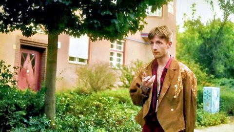 Handsome blond guy in fringed leather jacket with open shirt exposing chest outdoors