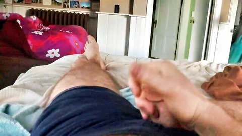 POV of man's legs in shorts on bed, feet visible, risky open door in background