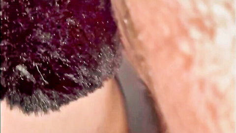 Extreme closeup of wet pink pussy lips surrounded by dark curly pubic hair
