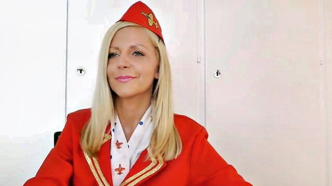Blonde flight attendant in sexy red uniform hat smiling teasingly