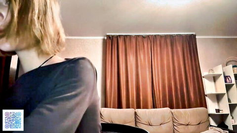 Skinny blonde webcam girl in black off-shoulder top teasing side profile in bedroom