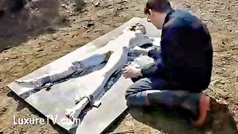 Man painting nude woman's body outdoors in desert fetish scene