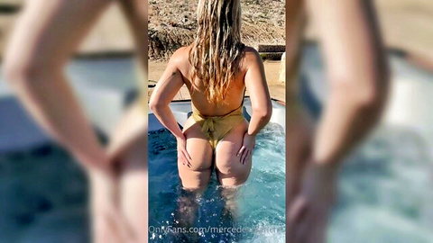 Mercedes Blanche in yellow bikini, wet blonde hair, big ass in hot tub from behind