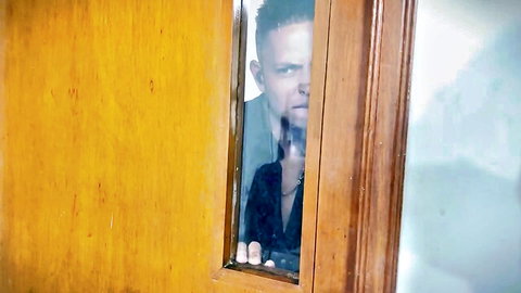 Intense man peeking through wooden door in teasing adult video scene