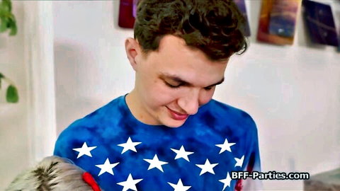 Curly-haired guy in starry blue shirt yanks blonde girl's ponytail smiling at BFF party