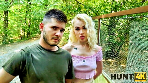 Young blonde in pink off-shoulder top pouting next to bearded guy outdoors in forest Hunt4K pickup