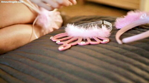 Teen princess placing pink feathered tiara and crown on bed with bare thighs teasing