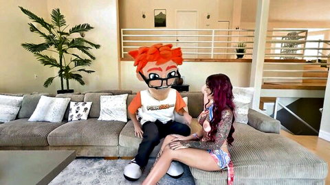 Petite tattooed redhead in skimpy bikini sitting with mascot on sofa