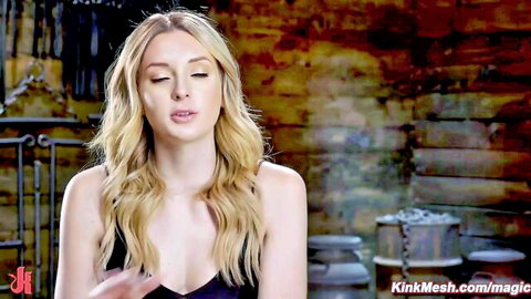 Skinny blonde BDSM slave teases cleavage in dungeon with intense pout