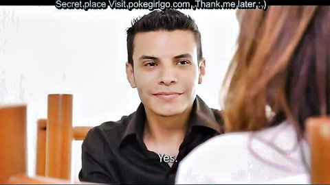 Smiling man in black shirt sits across from long-haired woman at wooden table chatting intimately