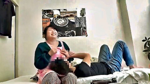 Playful Asian woman in pink apron teasing censored man on bed