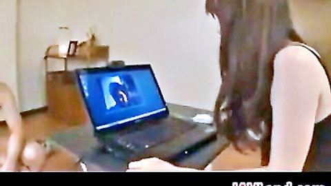 Japanese housewife with long dark hair typing on laptop in low-cut black top