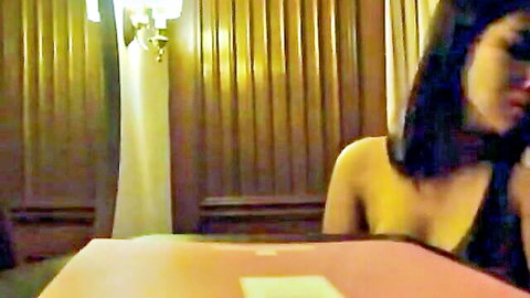 Myanmar actress Thazin in low-cut black dress, teasing at table, seductive pose