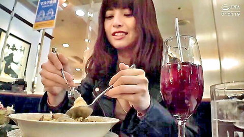 Smiling Asian woman eating bowl of food with wine glass in casual restaurant