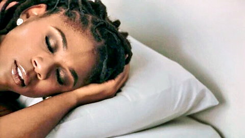 Beautiful ebony woman with dreadlocks sleeping peacefully on white pillow