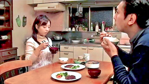 Japanese wife in apron dining intimately with man in kitchen