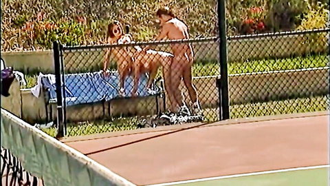 Two nude women on all fours fucked doggy style by naked men on outdoor tennis court