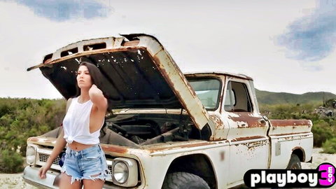 Brunette MILF in crop top and shorts posing by old truck, exposing toned body