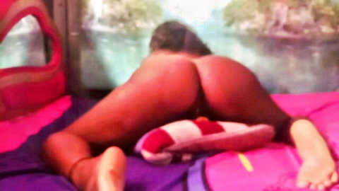 Ebony babe bends over spreading huge red ass and pussy on pink bed