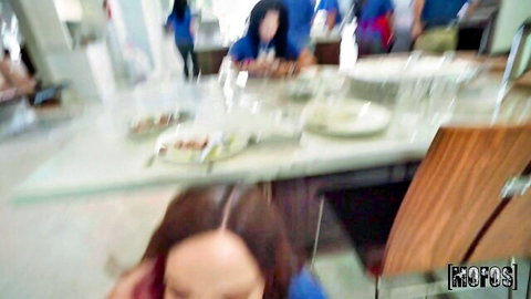 Blurry group of women in blue outfits around kitchen counter with food and chairs