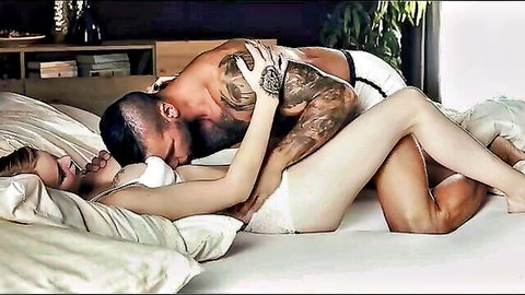 Ariela in white lingerie kissed by tattooed muscular man in passionate bed embrace