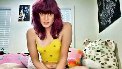 Petite purple-haired girl in tight yellow top teasing small tits and midriff on plushie bed