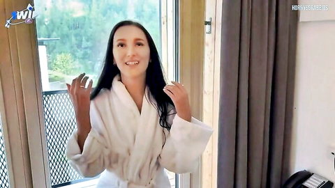 Brunette MILF in white robe on balcony, smiling tease