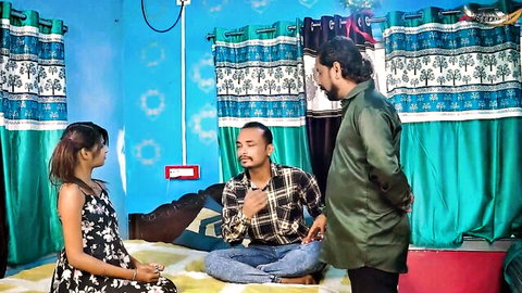 Young South Asian woman in dress sits on bed with two Indian men in kurta and shirt for taboo threesome