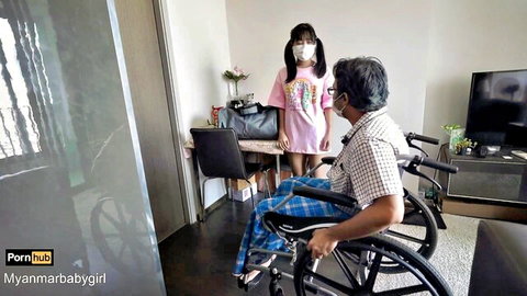 Petite Burmese girl in pink dress with older man in wheelchair