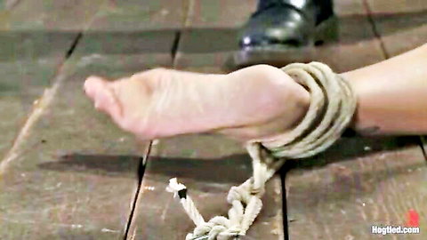 Amber Jayne bound in ropes, foot exposed in BDSM whipping scene