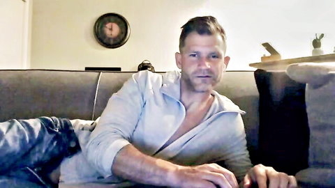 Muscular handsome man lounging on couch with open white shirt exposing toned chest