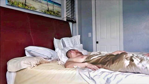Blonde man lying naked with open satin robe exposing hairy chest on bed