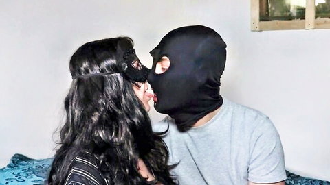 Brunette in black lace mask passionately tongues man wearing balaclava ski mask during intense amateur kiss