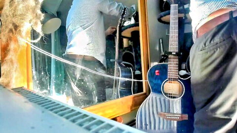 Clothed man in shirt and pants standing by guitar in mirror reflection amateur room shot