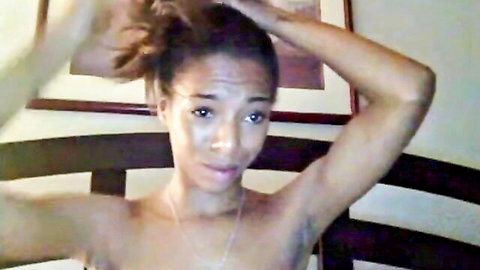 Topless ebony beauty with hair up, posing seductively in bedroom