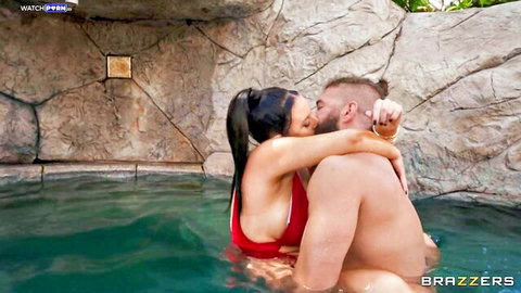 Angela White kissing muscular man in red bikini in pool