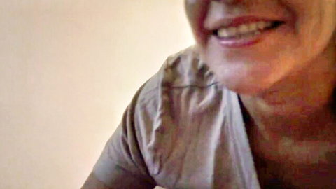 Smiling mature MILF in gray top teases with her award-winning breasts