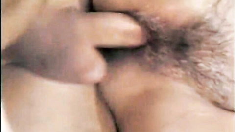 Hairy erect cock tip pressing against mature woman's bushy wet pussy lips closeup