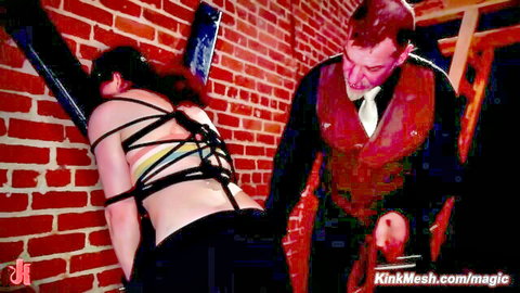 Bound brunette in BDSM rope play at swinger orgy, man in suit groping ass