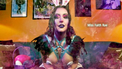 Gothic brunette Miss Faith Rae exposes small tits in feathered BDSM harness with bunny ears holding Easter basket